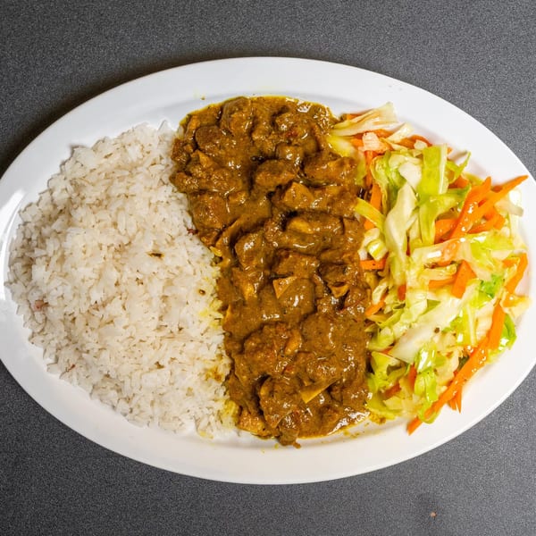 Curry chicken, white rice, and mixed vegetables on a white oval plate.