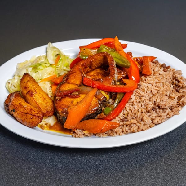 A white plate with brown rice, fried plantains, steamed cabbage, and brown stew fish with peppers.