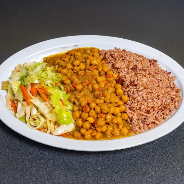 A white plate with chickpea curry, brown rice, and sautéed cabbage and carrots.